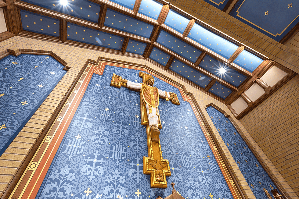 An ornate crucifix with Jesus in white and gold against a blue tile wall