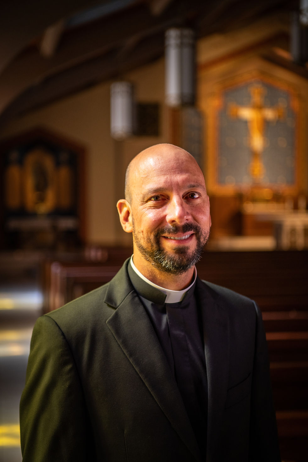 A priest in his clerics smiling while in church