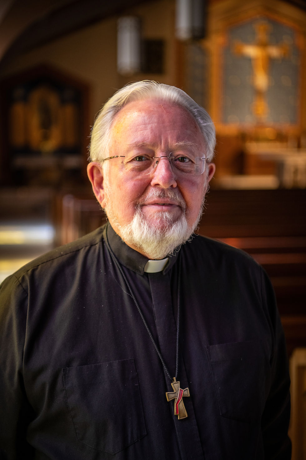 A priest in his clerics smiling while in church