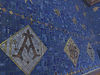 A dark blue mosaic wall with gold Christian symbols\